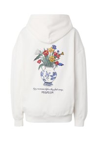 Sweat à capuche blanc avec une illustration de vase floral bleu et blanc tenant des fleurs colorées, et le texte « Profitez des moments avant qu'ils ne disparaissent » dans le dos.
