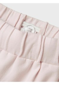Fascia elastica rosa chiaro con chiusura a bottone; presenta una texture a righe orizzontali e arricciature, offrendo un aspetto morbido.