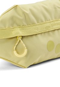 Gelbe Stofftasche mit strukturierter Oberfläche, ausgestattet mit einem dekorativen Reißverschluss-Zipper und drei runden Akzenten an der Seite.