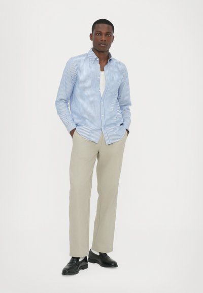 Camisa de botones a rayas azul y blanca, pantalones de vestir color crema y calzado negro. Tela fresca, corte ajustado y un diseño de cuello moderno.