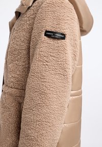 Beige sherpa fleece jas met een zwart stoffen label "Frieda & Freddies New York" op de bovenarm.