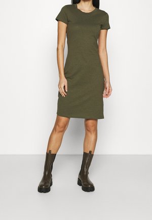Oliwkowa sukienka z krótkim rękawem w dopasowanym fasonie, wykonana z miękkiego materiału. Dopasowana do brązowych botków za kostkę z grubą podeszwą i elastycznymi bokami.