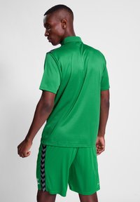 Grønt sportstøj bestående af en kortærmet skjorte med krave og matchende shorts. Materialet er let og glat med sorte sideaccenter.