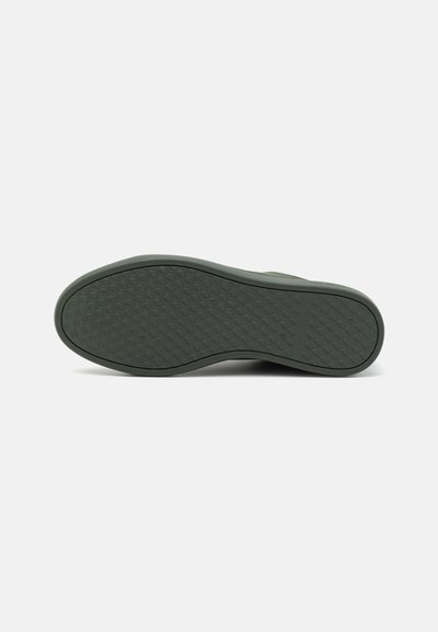 Green rubber shoe sole with a textured pattern, featuring a rounded shape and a slight arch at the midsole for support.