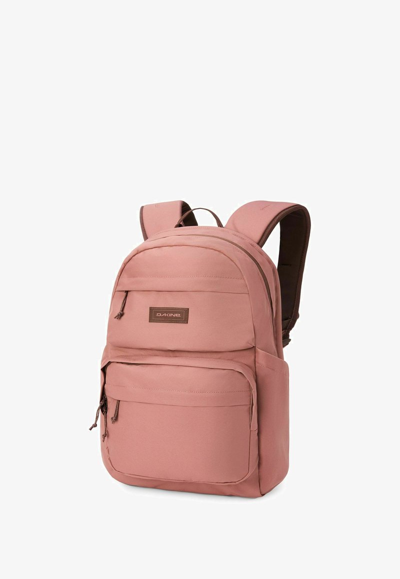 Mochila Dakine rosa con dos compartimentos con cremallera y correas acolchadas para los hombros, mostrada sobre un fondo blanco.
