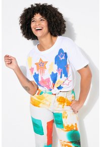 Hvid T-shirt med farverigt stjernetryk i blå, pink og orange. Komplementeret af flerfarvede mønstrede jeans med grønne og orange detaljer.