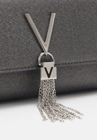 Clutch nera con una finitura testurizzata, accentuata da un hardware a forma di V in argento e una frangia a catena, dotata di una chiusura con un piccolo logo a forma di V.