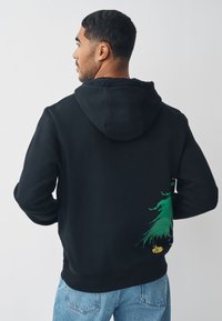 Zwarte hoodie met een groen boomgrafiek op de onderrug, voorzien van een gestructureerde stof, een capuchon met trekkoord en geribbelde manchetten.