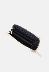 Portafoglio in pelle beige con interno nero, dotato di diversi scomparti per carte e di una tasca con zip, chiusa da una cerniera color oro.