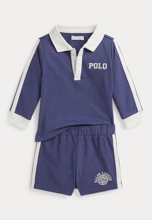 Sötétkék rövidnadrág szett, amely hosszú ujjú póló felsőből áll, fehér gallérral és hímzett "POLO" felirattal, hozzáillő sorttal és fehér oldalsávokkal.