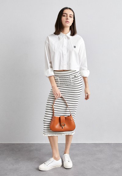 White cropped shirt, striped knee-length skirt, brown handbag, and white sneakers. Stripes are horizontal; skirt features pockets and a ruffled hem.