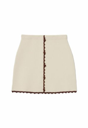 Jupe mini de couleur crème avec un bord festonné marron le long de l'ourlet et de la couture centrale. Fabriquée dans un tissu lisse, elle présente une coupe ajustée.