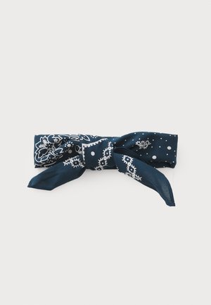 Marineblå silkesjal med hvite blomster- og prikkemønstre, bundet til en sløyfe med to lange ender for stilalternativer.