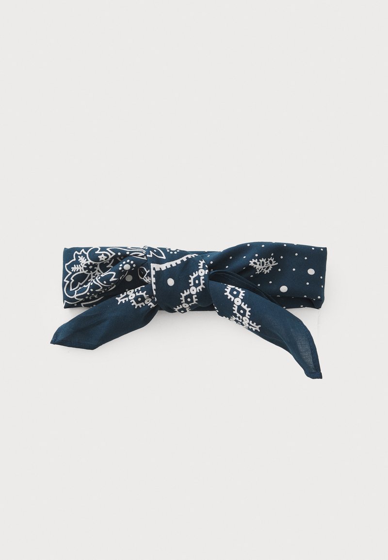 Navy blue silk scarf featuring white floral and dotted patterns, tied into a bow with two elongated ends for styling versatility.