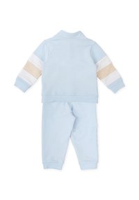 Conjunto de chándal de color azul claro hecho de una tela suave. La chaqueta presenta acentos a rayas en blanco y beige; los pantalones tienen puños y cinturilla elásticos.