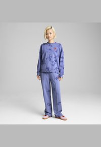 Felpa con tie-dye viola e pantaloni abbinati, caratterizzati da un design ricamato. Il tessuto sembra morbido, con una vestibilità comoda e maniche lunghe.