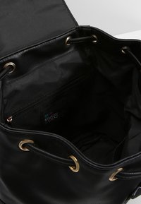 Borsa a secchiello nera in ecopelle con accessori in metallo dorato e chiusura a cordoncino. L'interno presenta una tasca con zip e un'etichetta con il logo.