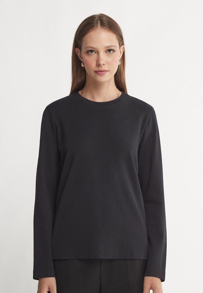 Zwarte langslavige shirt van zachte katoen met een ronde halslijn en een relaxte pasvorm, met een gladde textuur en een minimalistisch ontwerp.