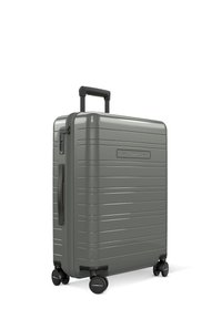 Valise rigide grise, dotée d'un design texturé à rayures, d'une poignée rétractable et de quatre roues noires pour une mobilité facile.