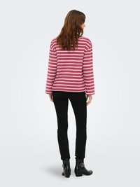 Haut à manches longues rayé en coton rose et blanc, coupe décontractée. Associé à un jean skinny noir et des bottines noires brillantes.