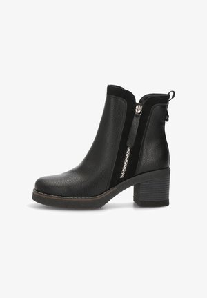 Botas negras hasta el tobillo con un upper de cuero texturizado, una cremallera lateral y un tacón apilado. El diseño presenta una forma ligeramente curvada.