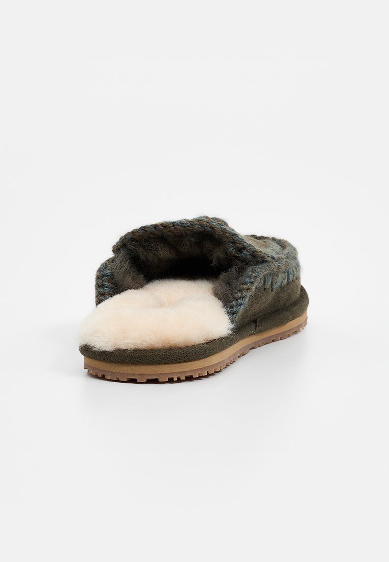 Groene wollen slippers met een zachte crème bontvoering, open teenontwerp en een gestructureerde zool. Blauwe geweven accenten op de bovenkant voegen detail toe.
