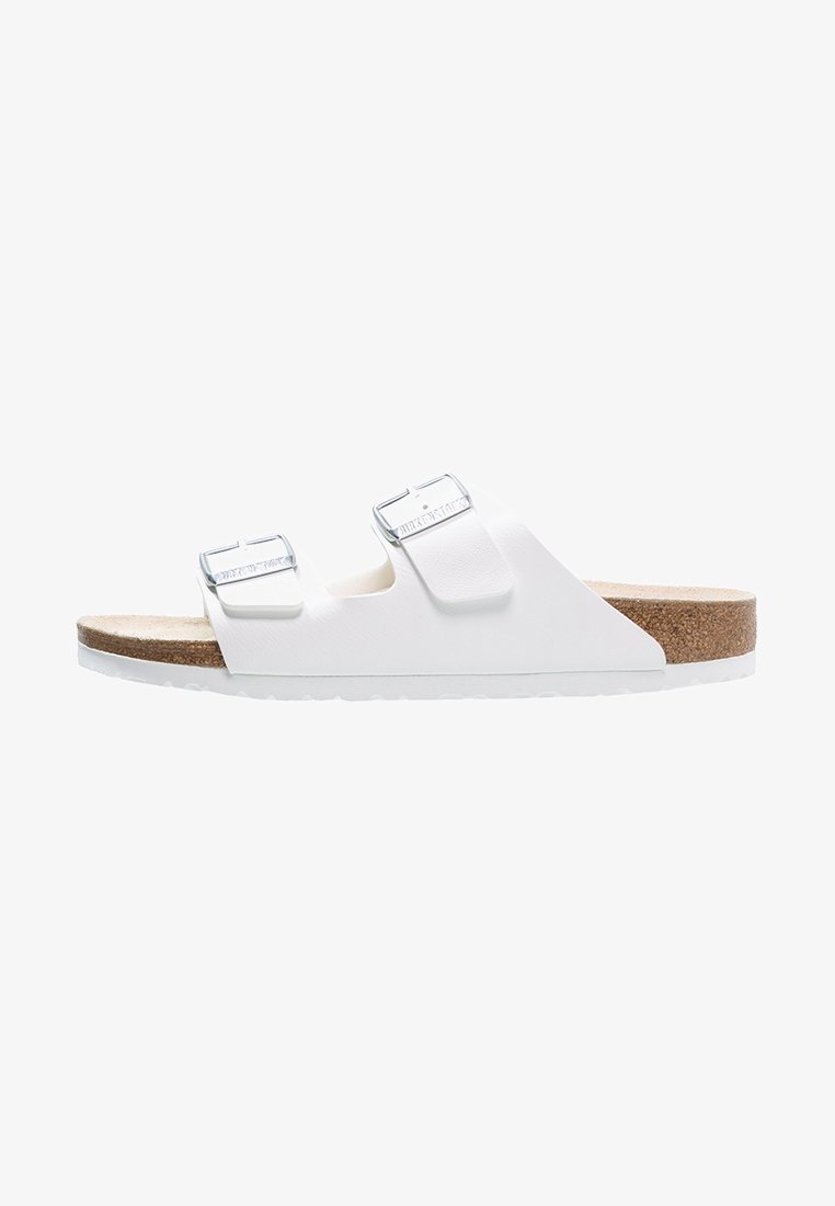 Sandal con due cinturini regolabili bianchi e fibbie argentate. Fodera in sughero con una suola bianca testurizzata. Design minimalista.