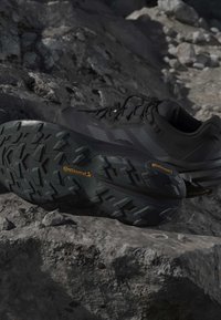 Chaussures de trail noires avec semelles Continental robustes reposant sur un terrain rocheux en plein air.