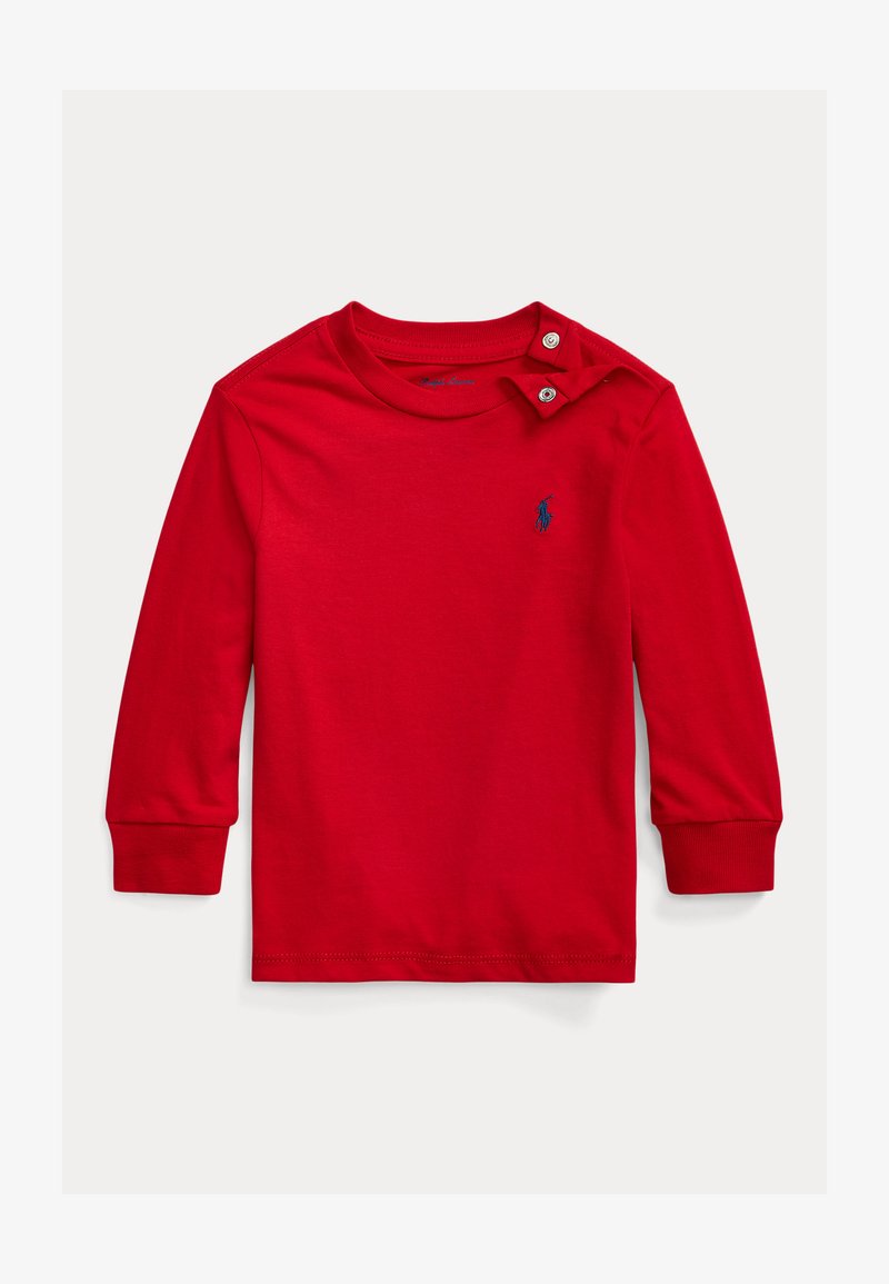 Raudona ilgomis rankovėmis marškinėliai iš medvilnės su apvalia apykakle ir spaustukų užsegimu ant peties. Ant marškinėlių yra mažas mėlynas logotipas.