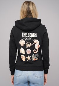 Čierna mikina s kapucňou so farebnou grafikou mušlí, kraba, koníka a koralov na chrbte, s nápisom "THE BEACH Club" nad nimi.