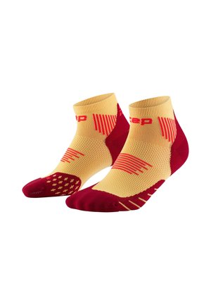 Yellow and red athletic socks featuring a ribbed design, a cushioned heel, and a patterned toe. Mid-length with contrasting colors and accents.
