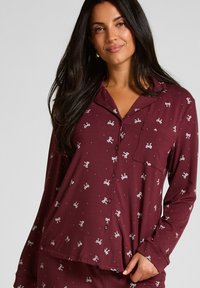 Bordeauxroze pyjamashirt met lange mouwen, witte strikpatronen, knoopsluiting en een borstzak; zachte stof; losse pasvorm.