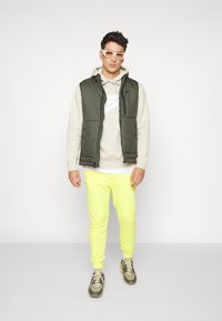Nike Sportswear CLUB JGGR - Tracksuit bottoms - yellow strike