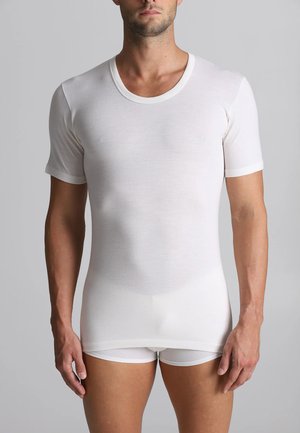 T-shirt bianco a maniche corte con scollatura rotonda. Tessuto liscio, design aderente, realizzato in materiale leggero. Indossato con pantaloni corti bianchi.
