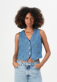 Jeans prsluk svijetloplave boje s V-izrezom, prednjim kopčanjem na dugmad, jednim džepom na grudima i skraćenim dizajnom. Mekana tekstura s vidljivim šavovima.