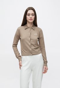 Brązowy dzianinowy kardigan z kołnierzem, zapinany na guziki, z prążkowanymi mankietami. Na piersi haft "2ND DAY" w białym kolorze.