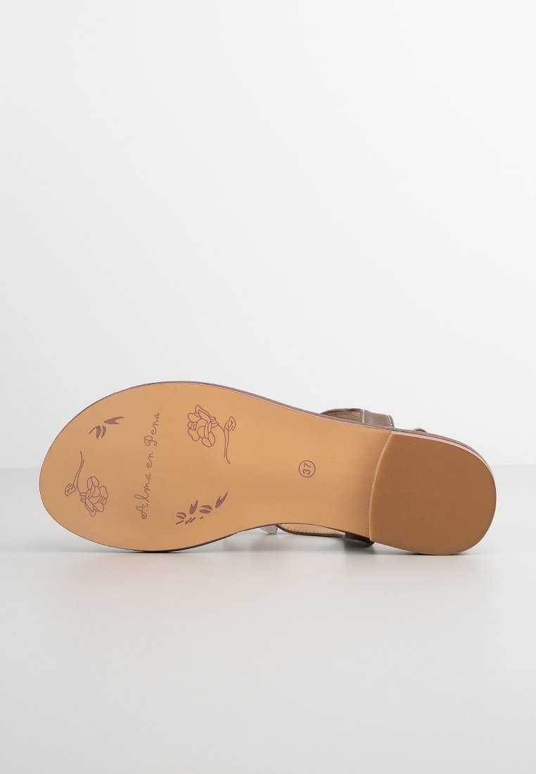 Braune Sandalensohle mit geprägtem Blumenmuster und Markenzeichen, die eine abgerundete Form und glatte Textur aufweist. Leichtes, flexibles Material.