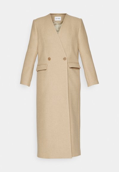 Cappotto in misto lana beige con doppio petto, colletto a punta, due tasche laterali e maniche lunghe. Tessuto liscio e vestibilità su misura.