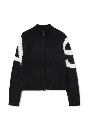 Zwarte cropped cardigan van donzig materiaal, met een ritsluiting en wit grafisch ontwerp op de mouwen. Geribbelde halslijn en boorden.