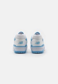 Paire de baskets New Balance blanches et bleu clair vues de dos sur un fond blanc.