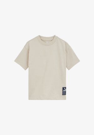 Tricou bej cu mâneci scurte și decolteu rotund, cu o mică aplicație albastru închis cu forme abstracte aproape de tiv, pe partea stângă.