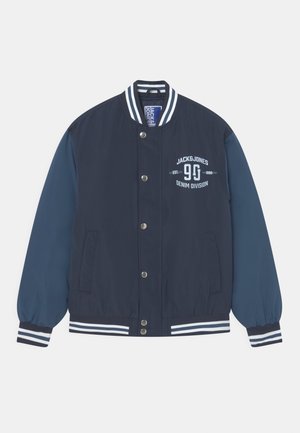 Veste bomber bleu marine avec des manches bleues contrastantes, des poignets rayés blancs et une fermeture à bouton-pression. Présente un logo sur la poitrine.