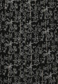 Tessuto nero con un motivo floreale bianco sparso e accenti metallici. Linee verticali attraversano il design creando un aspetto testurizzato.