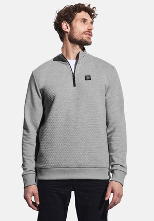 Suéter gris texturizado con cuello de media cremallera y un parche de logo negro en el pecho. Puños y dobladillo acanalados.