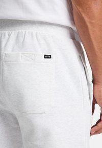 Lichtgrijze sweatpants van zacht materiaal, met een achterzak voorzien van een zwart label. Elastische tailleband voor comfort.