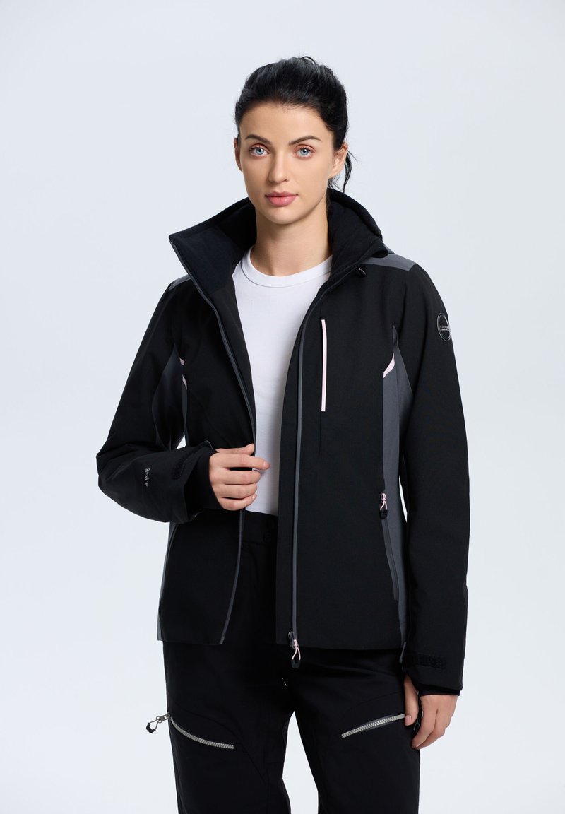 Giacca nera con dettagli grigi, colletto alto, tasche con zip e una texture liscia. Presenta un design aderente e un cappuccio regolabile.