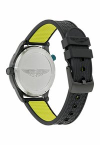 Reloj de caucho negro con correa texturizada, acentos verdes, fondo de acero inoxidable y corona azul; presenta la marca Aston Martin.