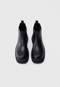 Bottes basses en cuir noir à finition lisse, avec des panneaux latéraux élastiques, un bout arrondi et une semelle en caoutchouc texturée pour une meilleure adhérence.
