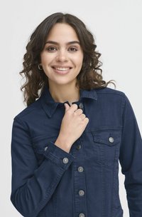 Sötétkék farmerdzseki gombos elejével, két mellzsebbel és patentos mandzsettával. Sima tapintású, fém gomb díszítéssel.