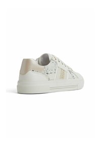 Sneakers bianchi con tomaia in tessuto testurizzato, tallone liscio e lucido, e suola in gomma. Presentano borchie decorative e strisce sottili sui lati.